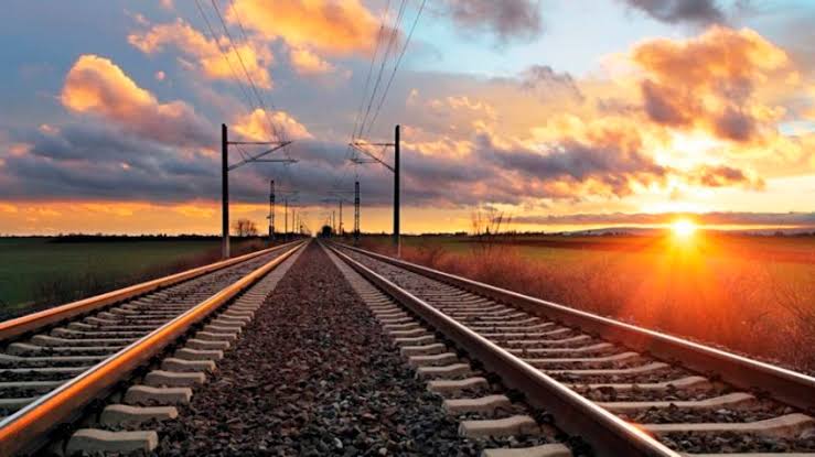 Uma Ferrovia mostrandos os trilhos em céu aberto entardecendo 
