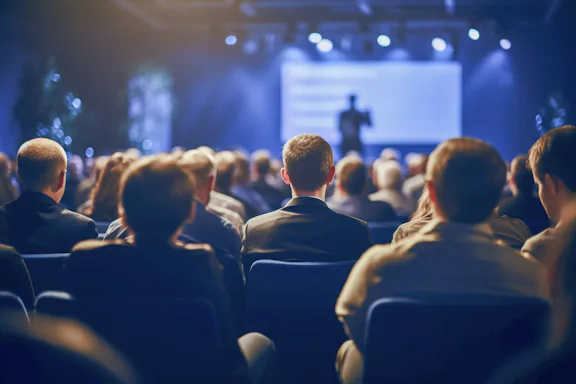 Imagem de auditório de evento com pessoas sentadas olhando para o palco