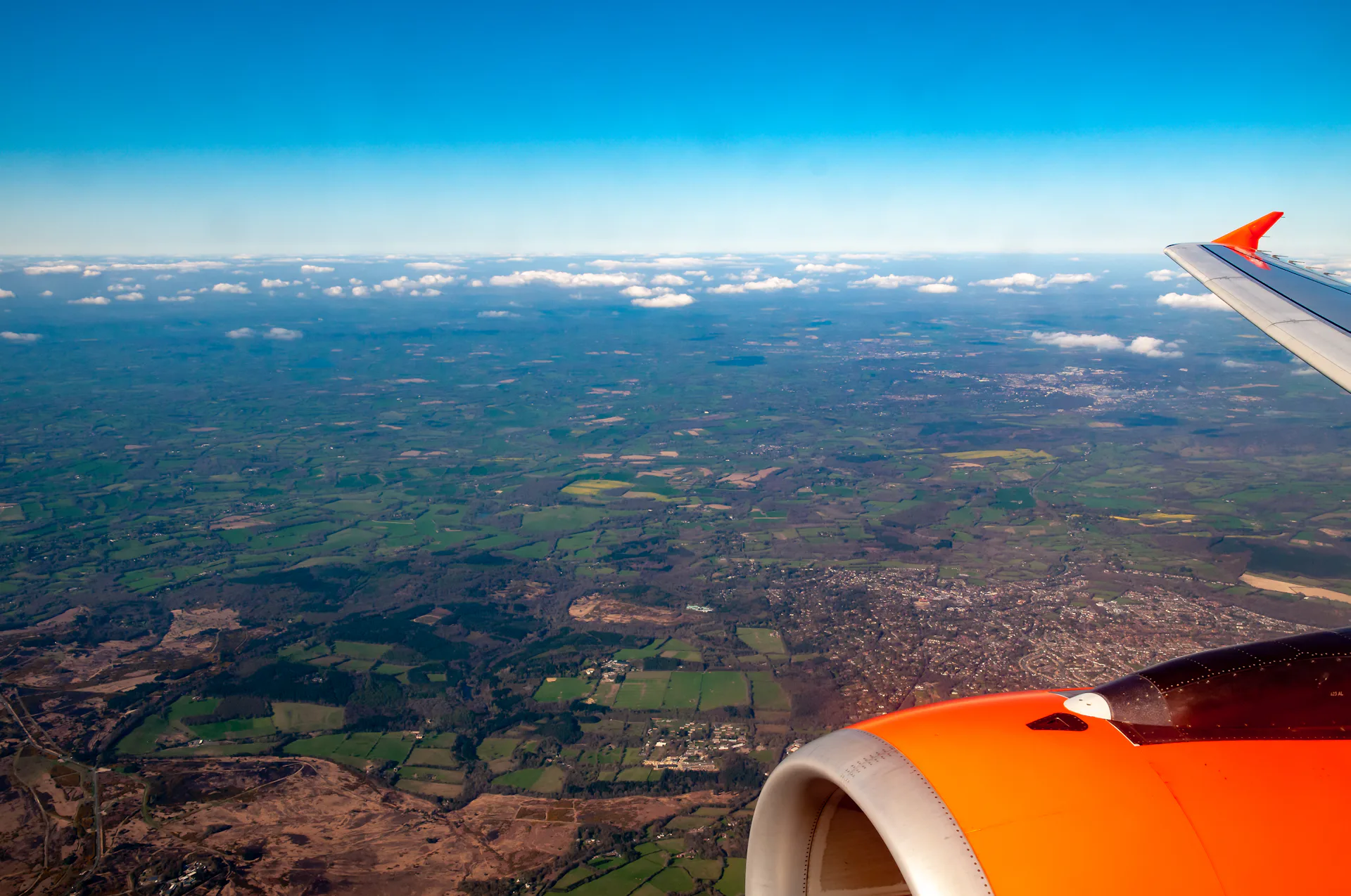 Foto tirada da janeira de um avião com a paisagem vista do céu de um campo verde