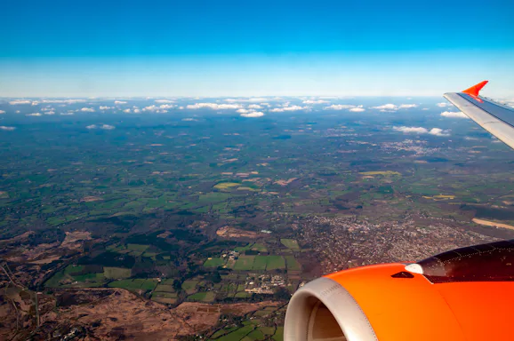 Foto tirada da janeira de um avião com a paisagem vista do céu de um campo verde 
