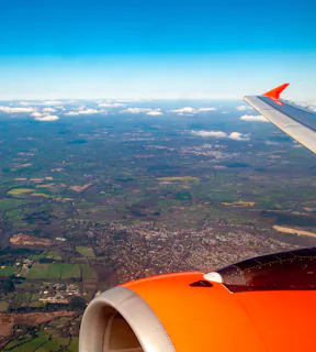 Foto tirada da janeira de um avião com a paisagem vista do céu de um campo verde 
