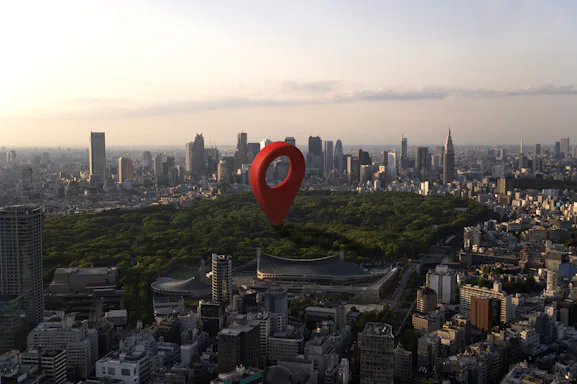 Imagem de uma cidade vista de cima, com um drone, e um pin de localização vermelho no meio. Imagem Freepik