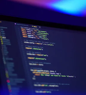 Foto de uma tela de um notebook em perspectiva mostrando um editor de texto com código de programação