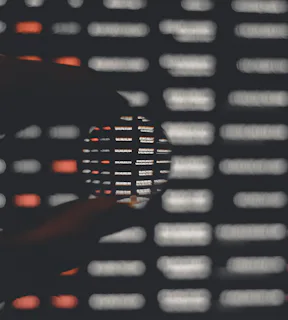 Imagem de uma mão segurando uma lupa e olhando alguns códigos.