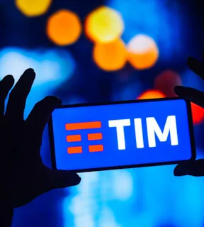 Imagem de uma pessoa segurando o celular com o logo da TIM.